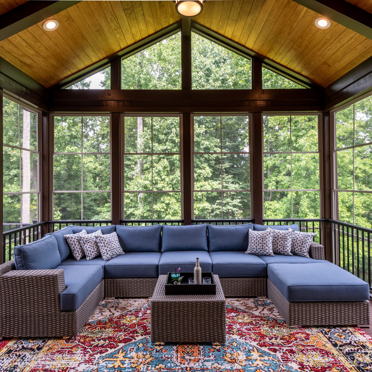 New modern screened porch with patio furniture, summertime woods in the background. New home addition concept.