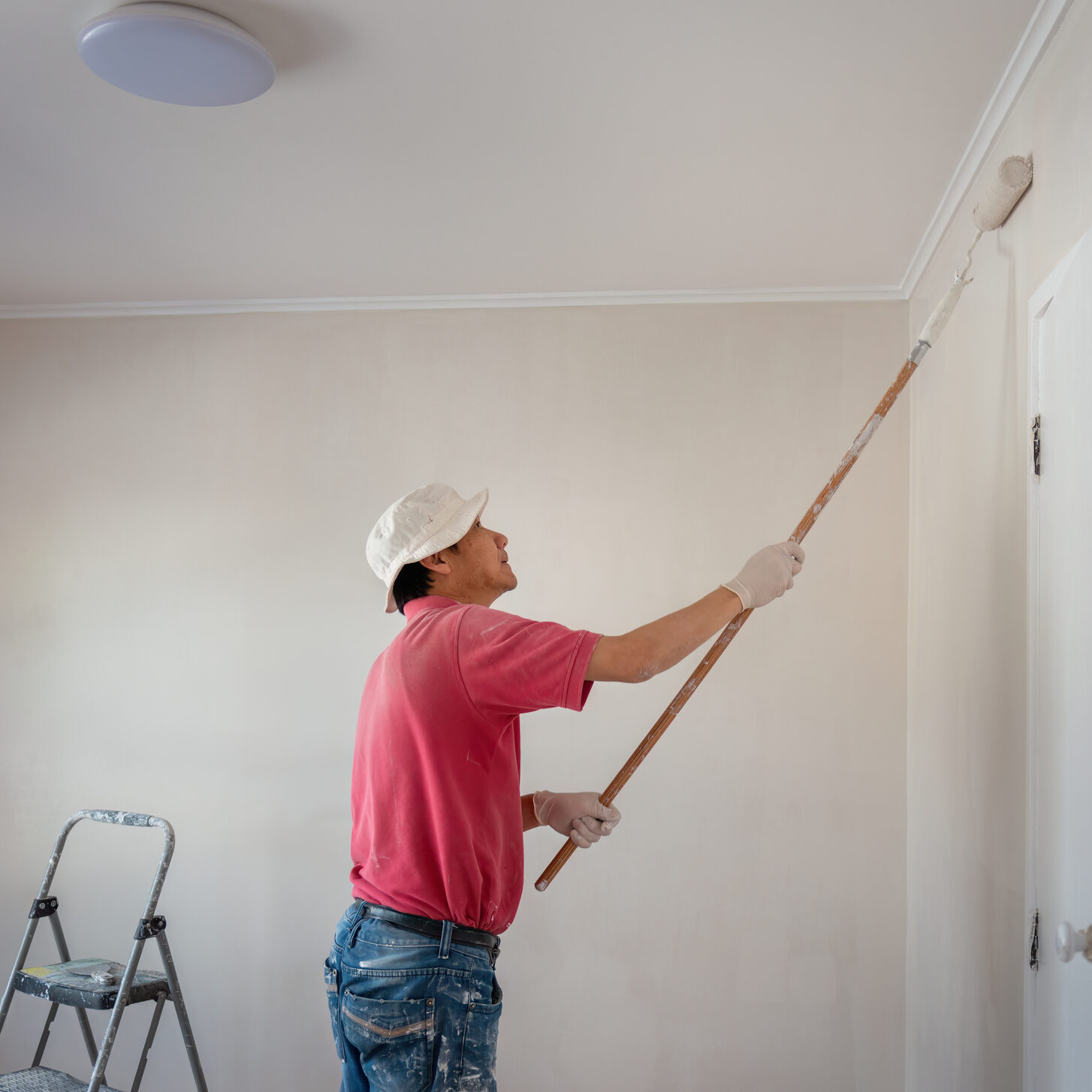 Man painting wall with a roller in home renovation project